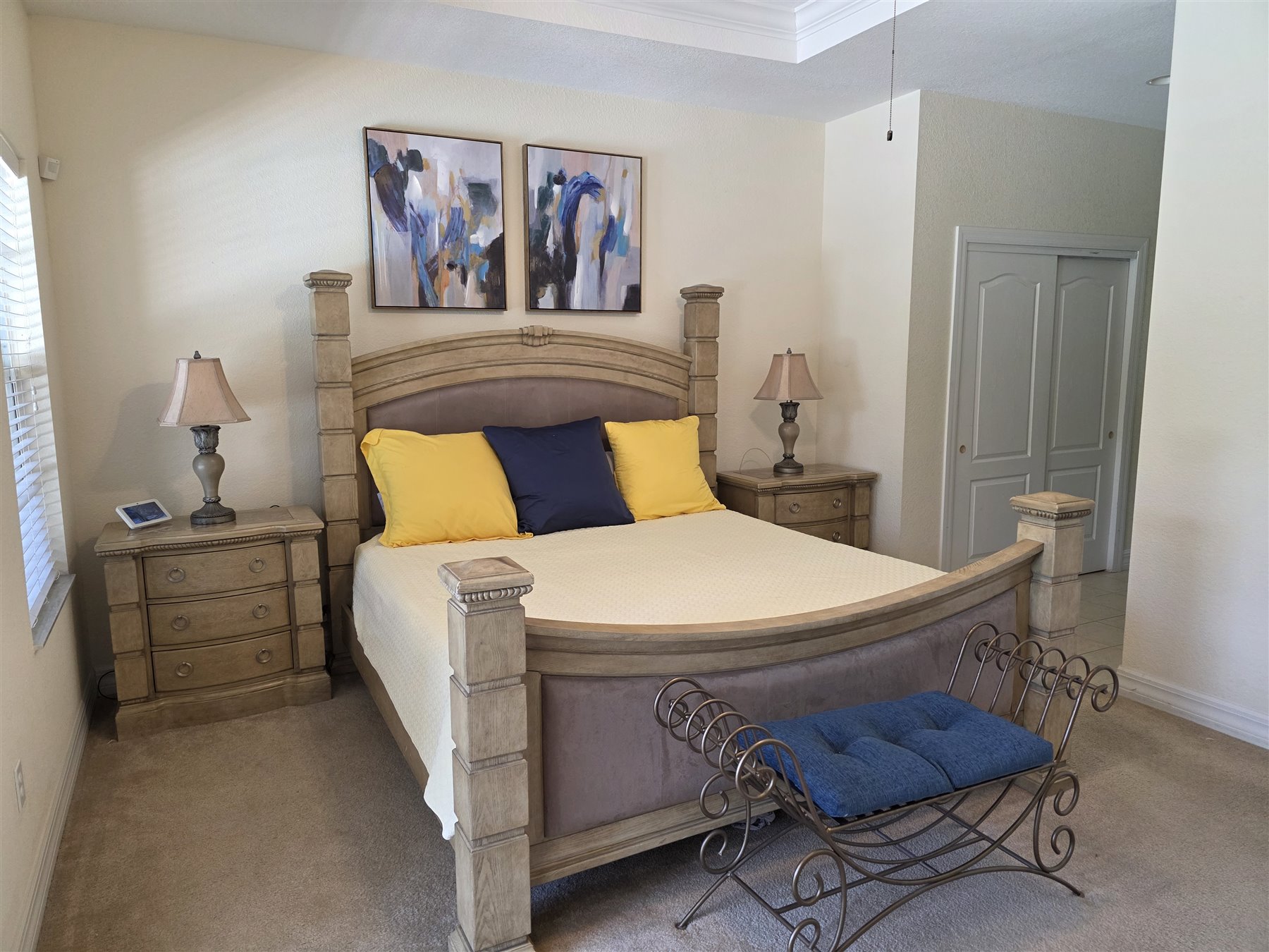 Primary suite bed with yellow and navy pillows